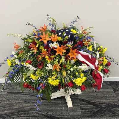 Large patriotic floral spray with red, white, and blue flowers and an American flag