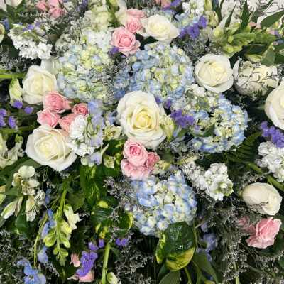 Large mixed floral arrangement with white roses, blue hydrangeas, and pink spray roses
