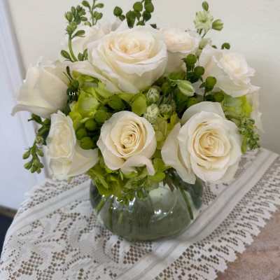 White roses and green hydrangeas in a glass vase