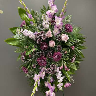 Standing floral spray with pink and purple flowers on a wire easel