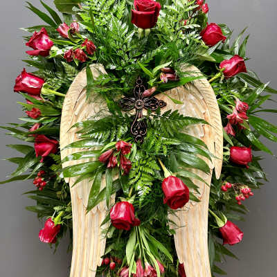 Standing floral spray with red roses and a wooden angel-wing cross