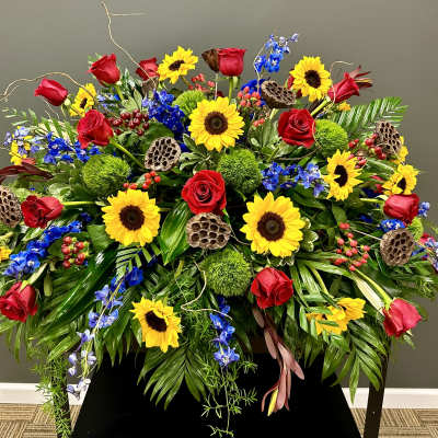 Large arrangement of red roses, sunflowers, and blue flowers
