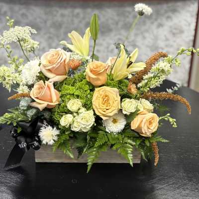 Peach roses and pale lilies arranged in a wooden box