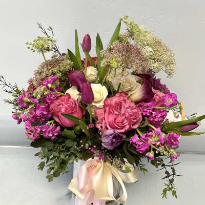 Bouquet of pink roses, purple tulips, and white calla lilies in a vase