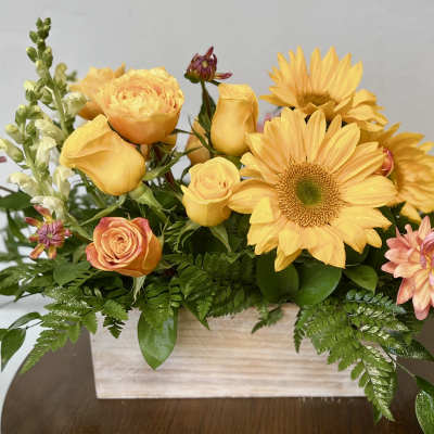 Low yellow and peach floral arrangement with sunflowers and roses in a rectangular wooden box