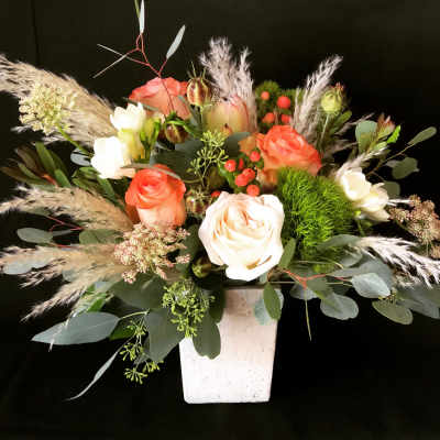 Mixed rose arrangement in a white square vase with airy grasses