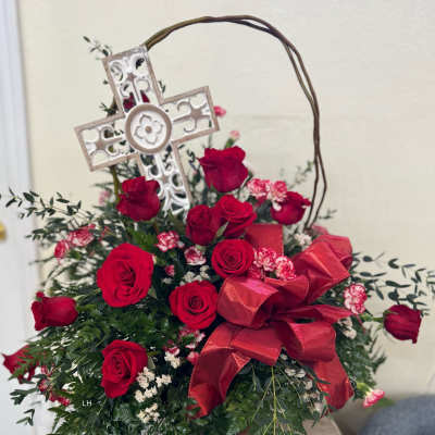 Red roses arranged with a decorative cross and ribbon