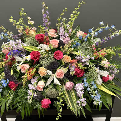 Large mixed floral arrangement with roses, lilies, and blue delphinium