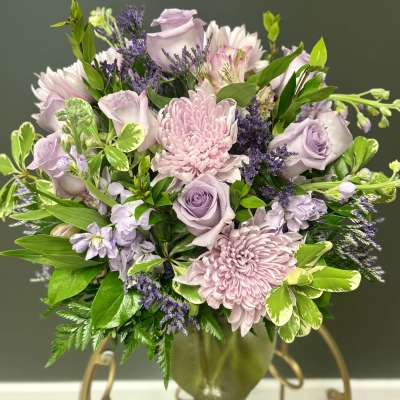 Lavender roses and pink chrysanthemums arranged in a glass vase
