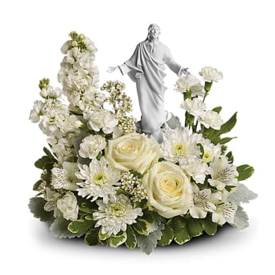 White floral arrangement with roses and mums surrounding a white Jesus figurine