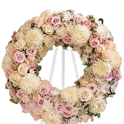 Pastel pink and cream floral wreath displayed on a white easel stand