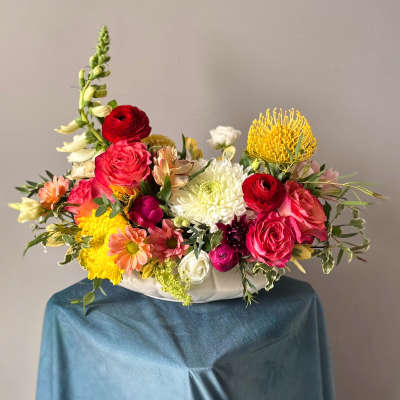 Colorful mixed flower arrangement in a white bowl vase