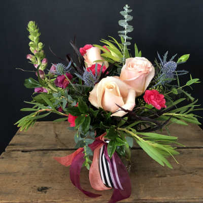Bouquet of peach roses and pink flowers in a glass vase
