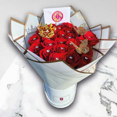 Bouquet of red roses in white wrapping with a small crown topper