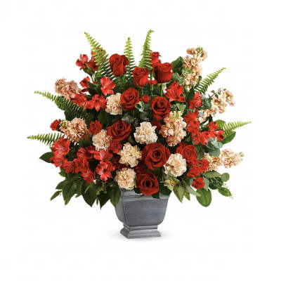 Large arrangement of red roses, red accent blooms, and cream carnations in a gray pedestal vase