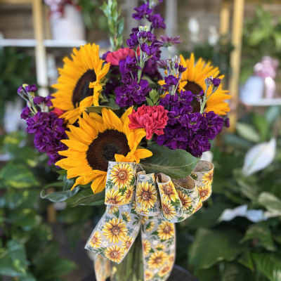 Sunflower bouquet with purple blooms in a glass vase and sunflower ribbon