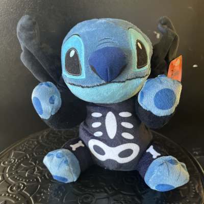 Blue Stitch plush toy with raised arms and a black skeleton costume