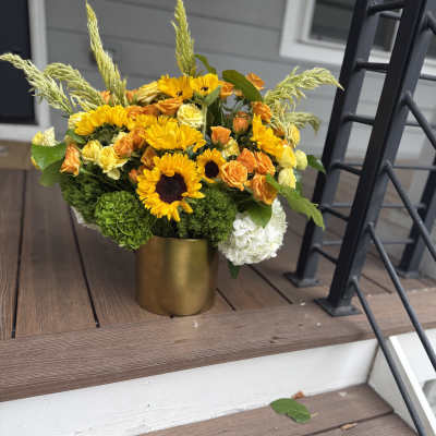 Yellow and orange flowers arranged in a gold vase