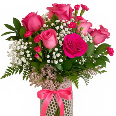 Pink roses and carnations in a glass vase with a pink ribbon
