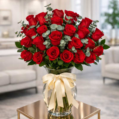 Bouquet of red roses in a glass vase with a cream ribbon