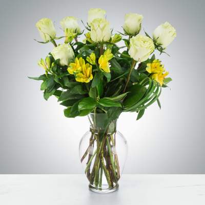 Clear glass vase of white roses and yellow alstroemeria in a mixed bouquet