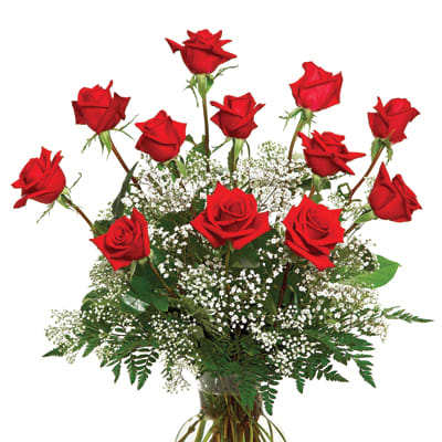 Tall arrangement of red roses with white filler flowers in a clear glass vase
