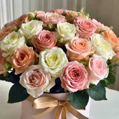Pink and white roses arranged in a round hatbox with a ribbon