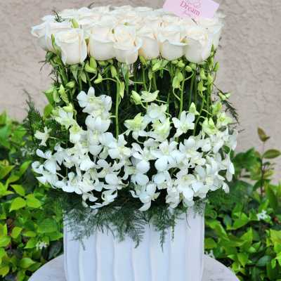 White roses and cascading white orchids in a white vase