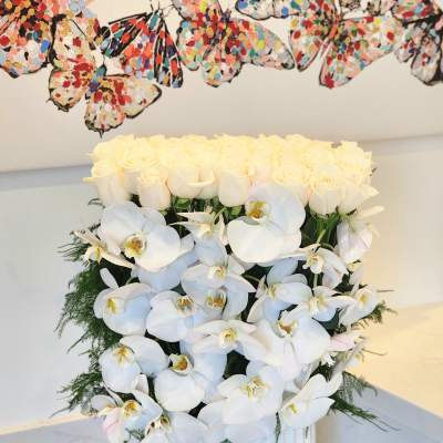 White roses and orchids arranged in a ribbed white vase