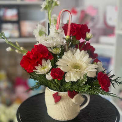 Red and white flowers arranged in a mug with a candy cane handle
