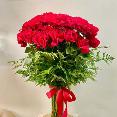 Red roses in a clear glass vase with a red ribbon