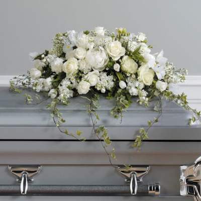 White rose and lily casket spray with trailing ivy on a silver casket