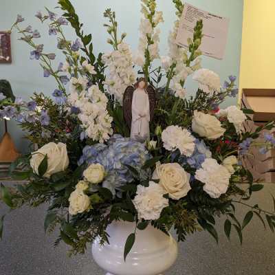 White and blue floral arrangement in a white urn with a small angel figurine