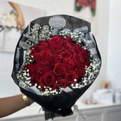 Bouquet of red roses with white baby's breath in black wrapping