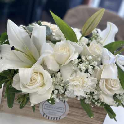 White roses and lilies arranged in a wooden box