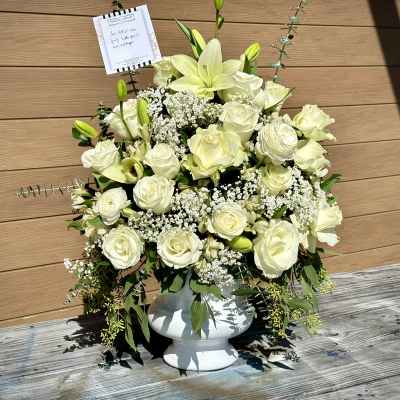 White rose and lily arrangement in a white pedestal vase