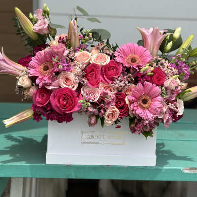 Pink roses and gerbera daisies arranged in a white box