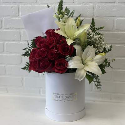 Red roses and white lilies arranged in a white hat box