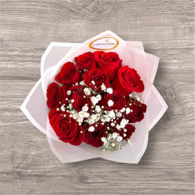 Bouquet of red roses with small white filler flowers in pale wrapping