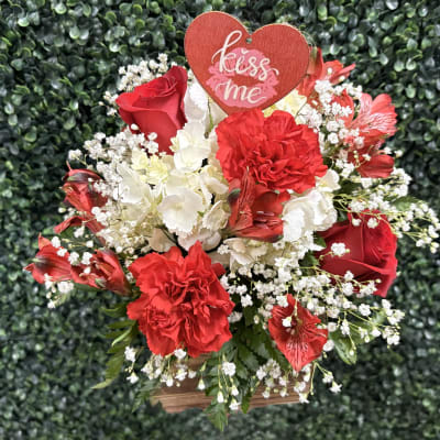 Red and white floral arrangement with a heart "kiss me" sign