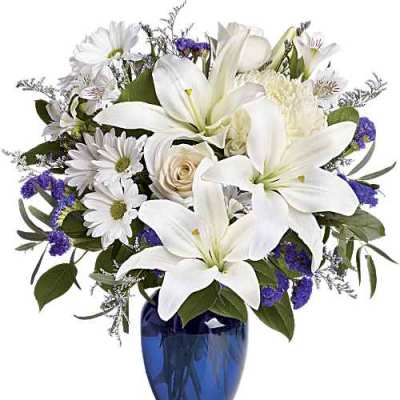 White lilies and daisies in a blue glass vase