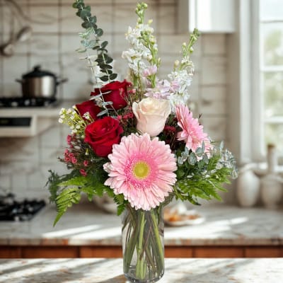 Mixed bouquet of pink and red flowers in a glass vase