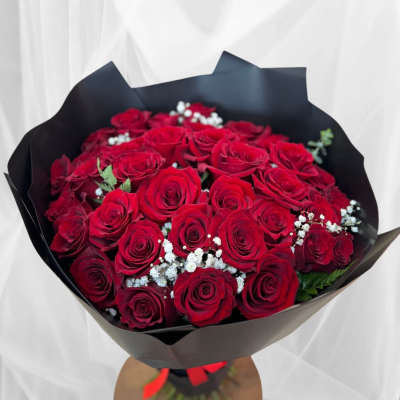 Bouquet of red roses with white baby's breath in black wrap