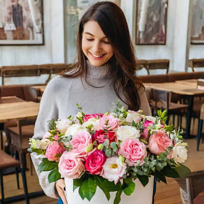 Woman holding a large box of pink and white roses