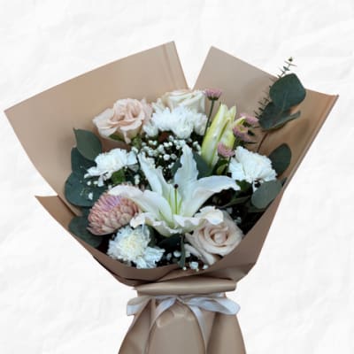 Bouquet of white and blush flowers wrapped in tan paper