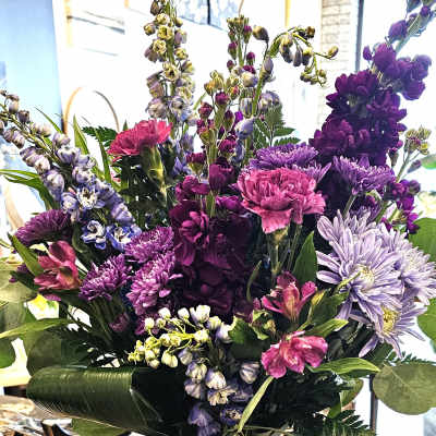Purple and pink mixed bouquet in a glass vase with a navy ribbon