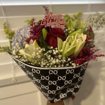 Bouquet of red roses and pale lilies with a Valentine topper