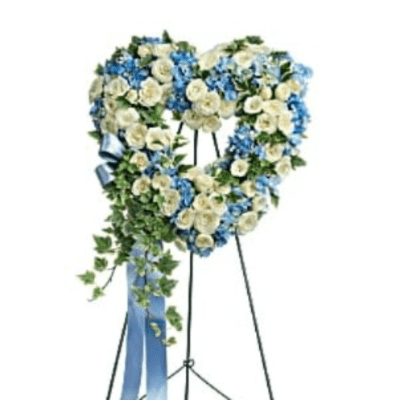 Heart-shaped floral wreath on a stand with white and blue flowers