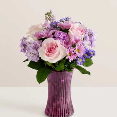 Pink and lavender flower bouquet in a purple glass vase