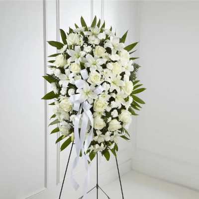 White funeral spray on a standing easel with ribbon
